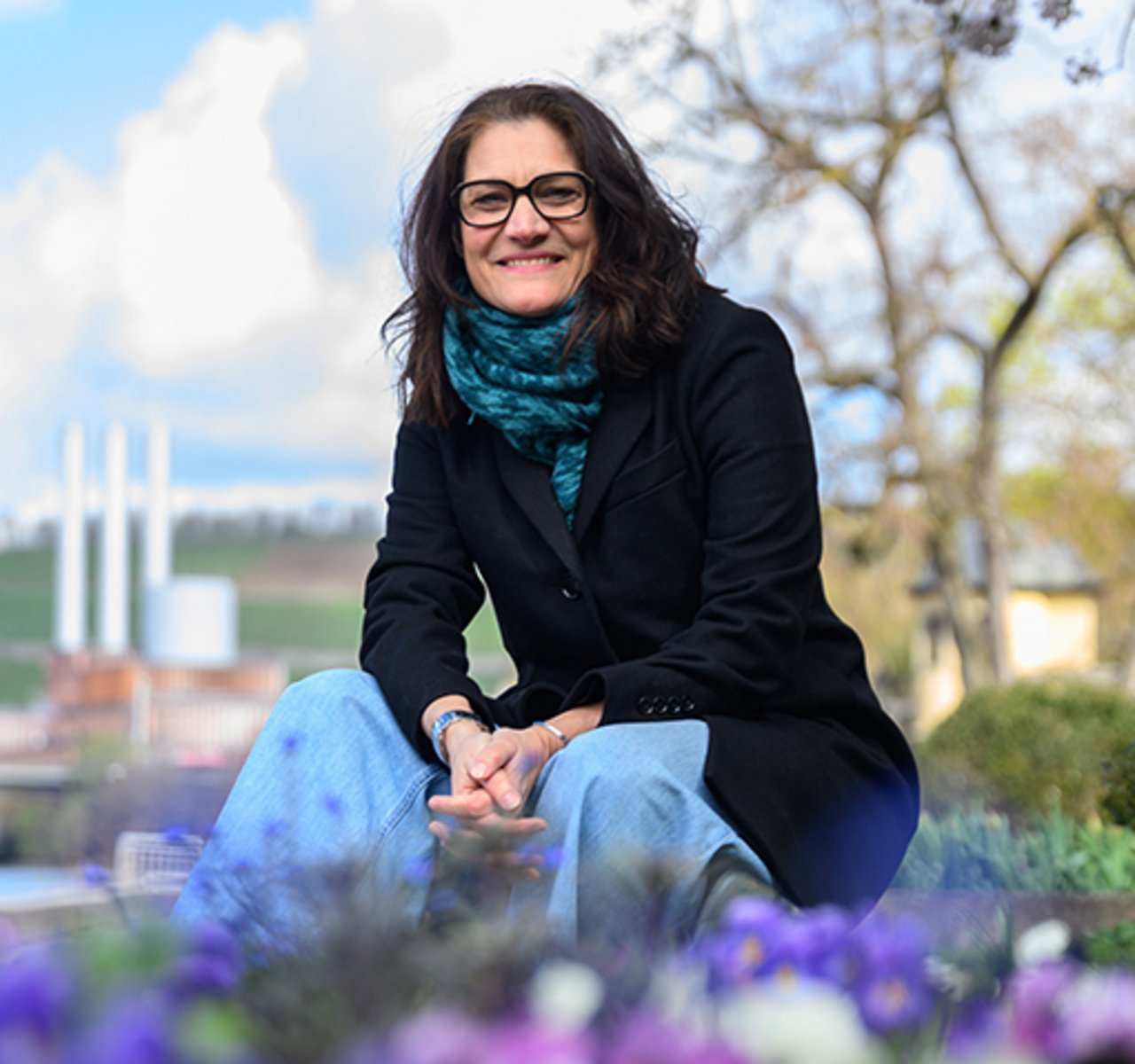 Melanie Dertinger sitzend vor Weinbergen und Bäumen